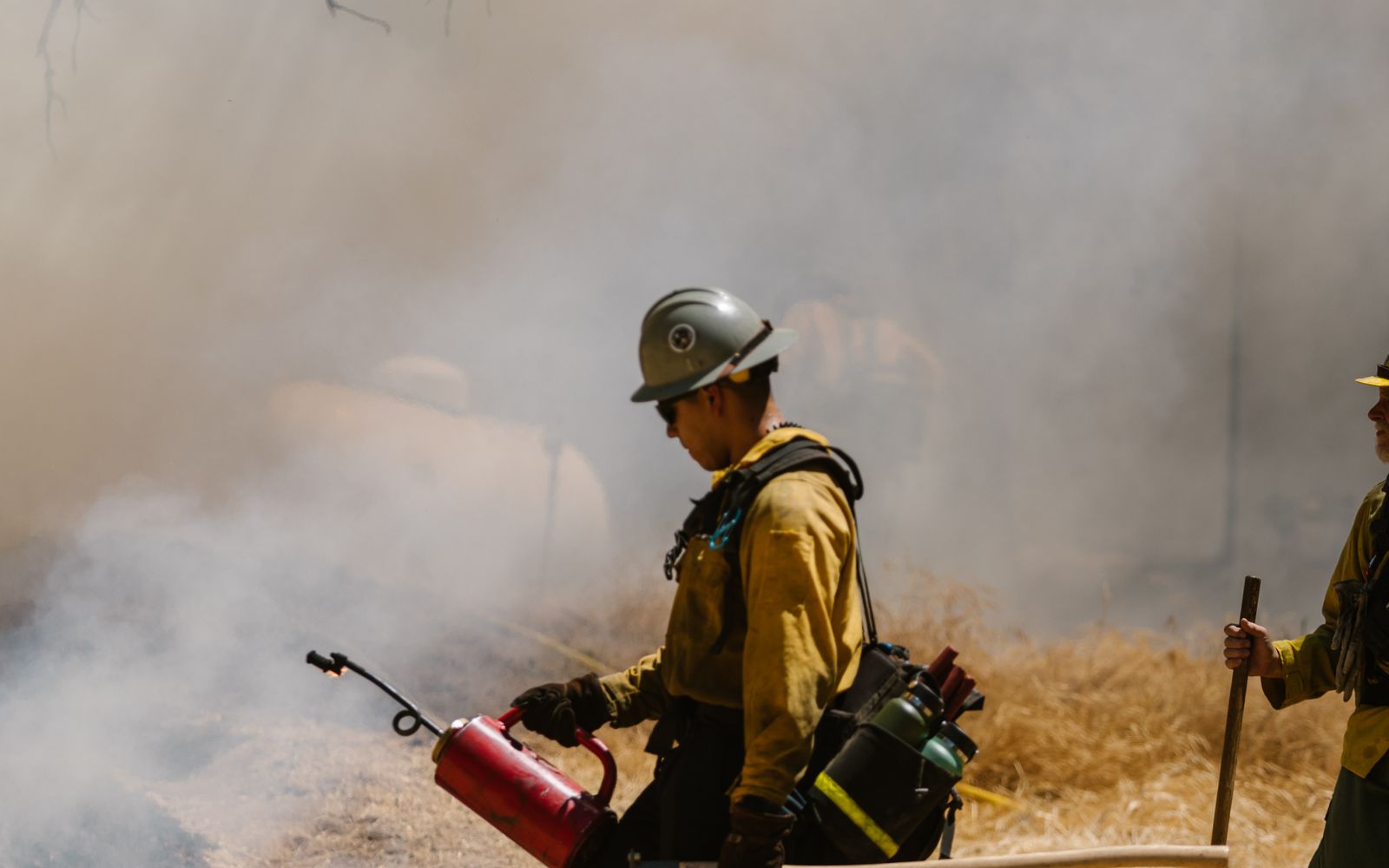 Firefighters working a blaze amid smoke and dry grass in Sequoia National Park, California.