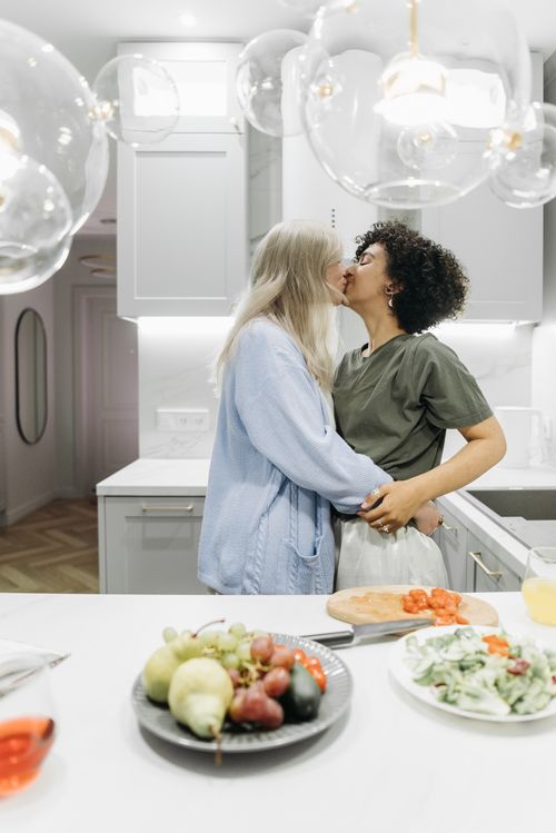 Free A loving couple shares a tender moment in their stylish kitchen with fresh vegetables. Stock Photo