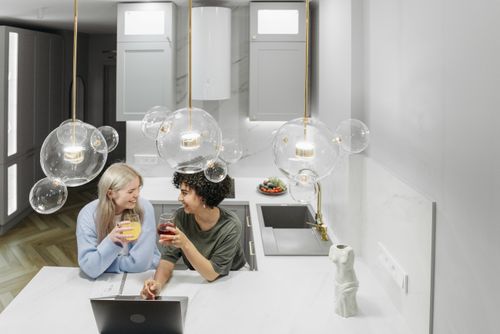 Free A joyful couple enjoying drinks and conversation in a stylish kitchen setting. Stock Photo