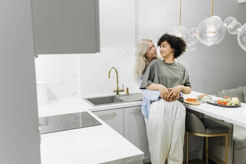 Free Two women sharing a loving moment in a stylish kitchen, highlighting LGBT pride and affection. Stock Photo