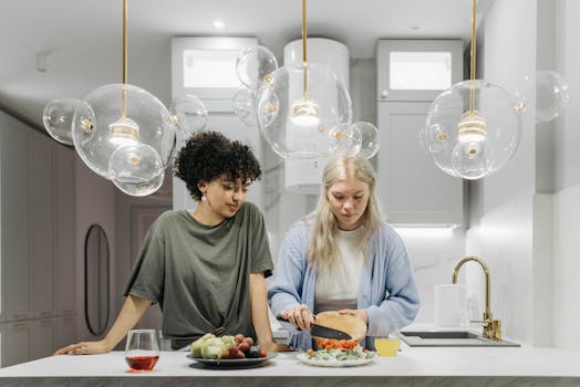 Two women preparing a fresh meal in a brightly lit modern kitchen with elegant lighting.