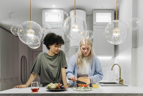 Free Two women preparing a fresh meal in a brightly lit modern kitchen with elegant lighting. Stock Photo