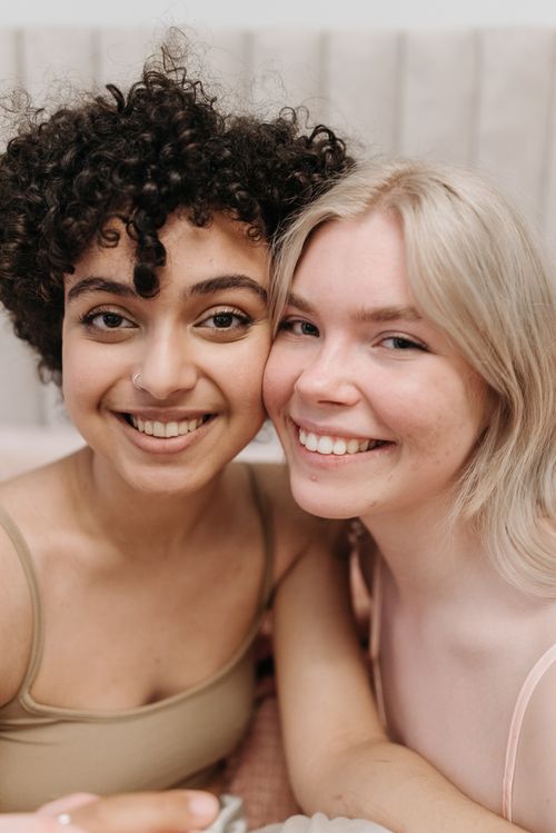 Free A heartwarming close-up portrait of two young women smiling warmly at the camera, showcasing friendship and joy. Stock Photo