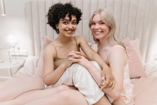 Free Smiling couple holding hands on a bed, enjoying a cozy, intimate moment indoors. Stock Photo