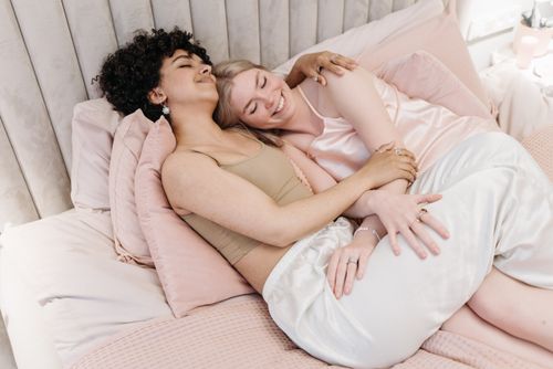 Free Happy LGBTQ+ couple embracing on a bed, sharing a tender moment of love and togetherness. Stock Photo