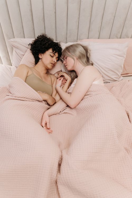 Free Two women lovingly rest together in bed, embracing closeness and affection. Stock Photo