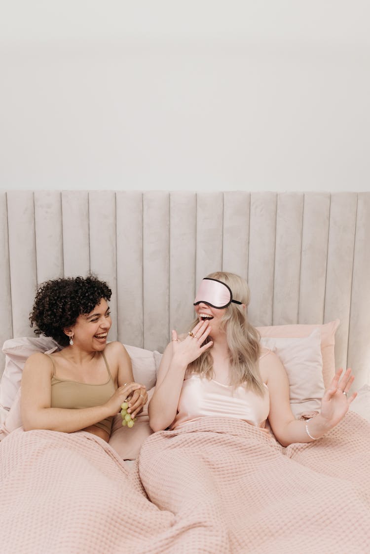 Women Laughing While Lying On Bed