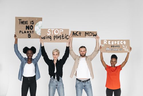 Free Four diverse individuals hold protest signs advocating for environmental change in a studio setting. Stock Photo