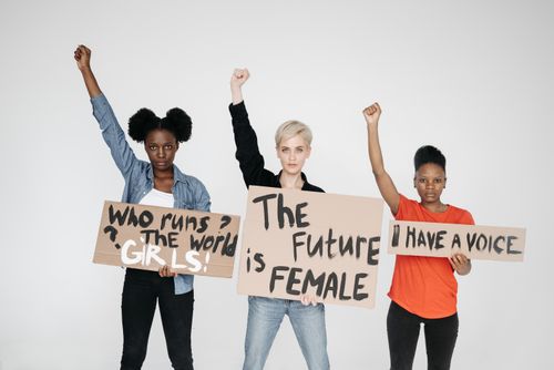 Free Diverse women raising fists and holding feminist signs, showcasing empowerment and unity. Stock Photo