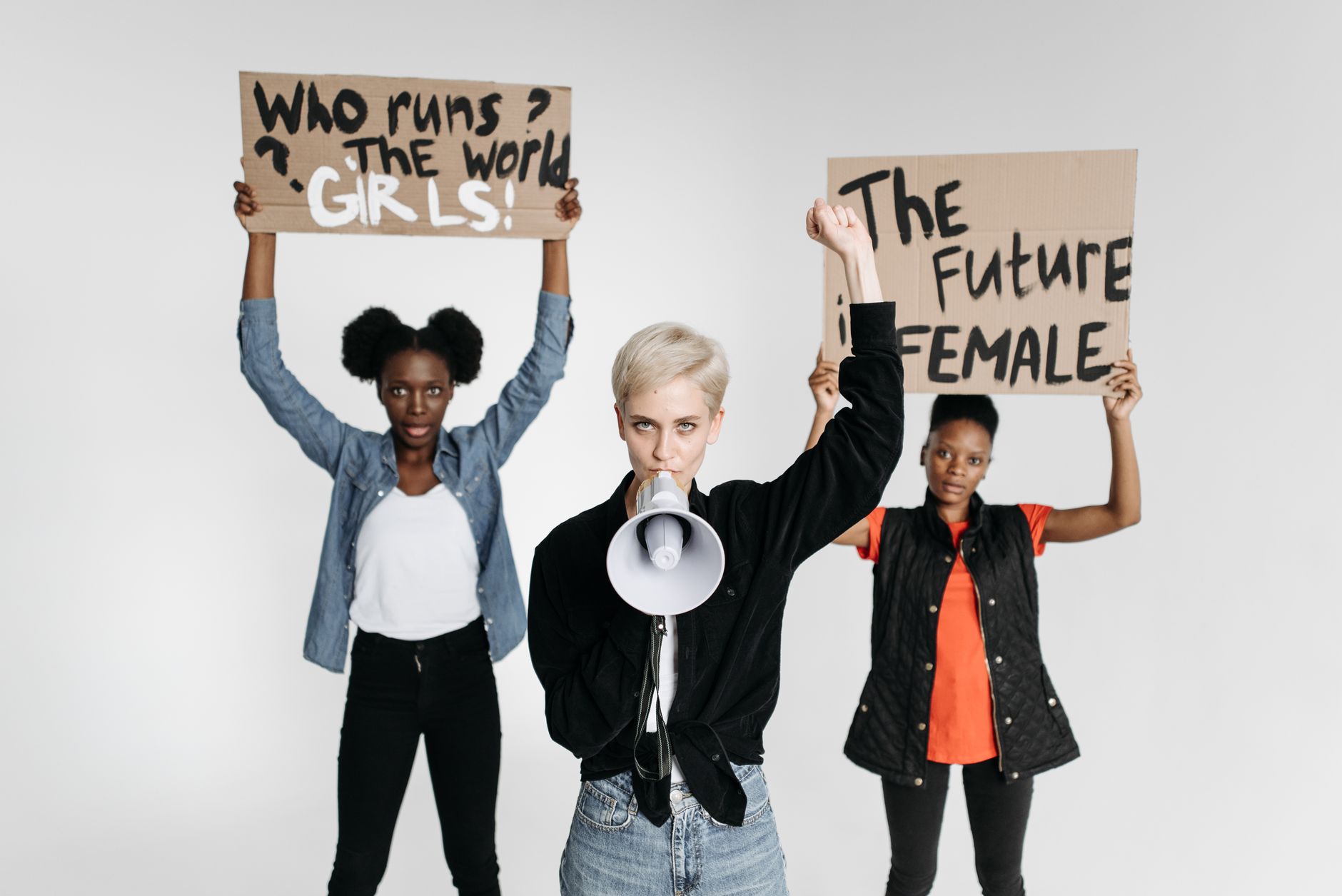 Diverse women protesting with placards and megaphone in a studio setting.