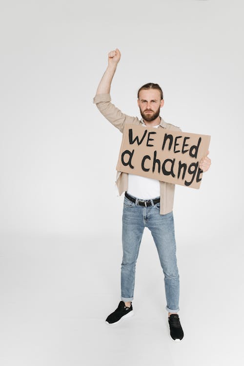 Man with a Raised Fist and a Protest Sign Demanding Change 