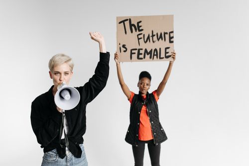 Free Two women advocating feminism with a sign 'The Future is Female' and a megaphone, standing indoors. Stock Photo
