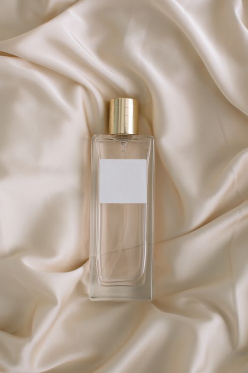 Free Minimalist perfume bottle on luxurious satin fabric, ideal for fashion and design themes. Stock Photo