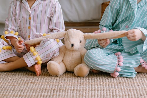 Close-up of Children Sitting with a Teddy Bear Between Them 