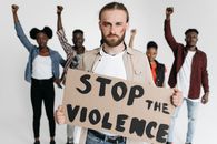 Man with Bruise on Cheek Holding 'Stop the Violence' Poster