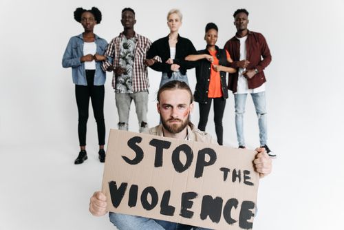 Free A group of people holding a cardboard sign that reads 'Stop the Violence' during a studio protest shoot. Stock Photo