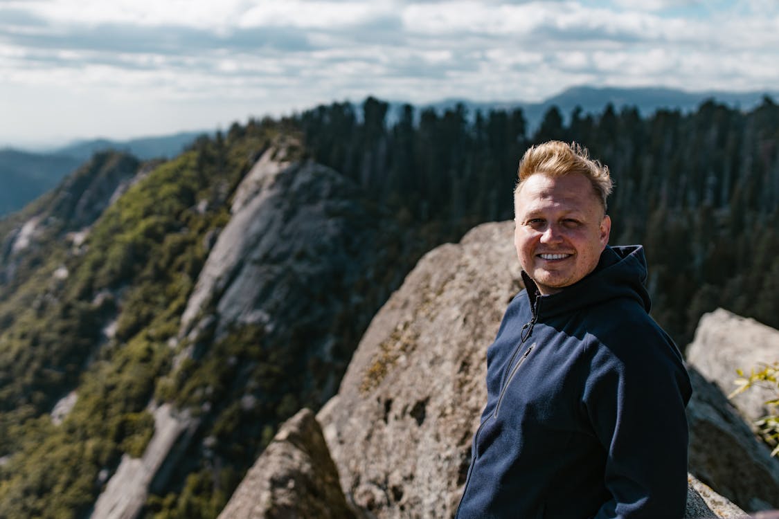 Man in Blue Jacket Standing on Rock