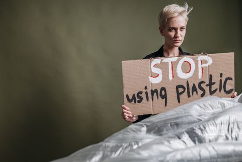 Free Portrait of an adult woman holding a sign urging to stop plastic usage. Stock Photo