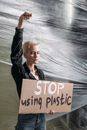 A determined activist holds a sign that reads 'STOP using plastic' against a plastic backdrop.