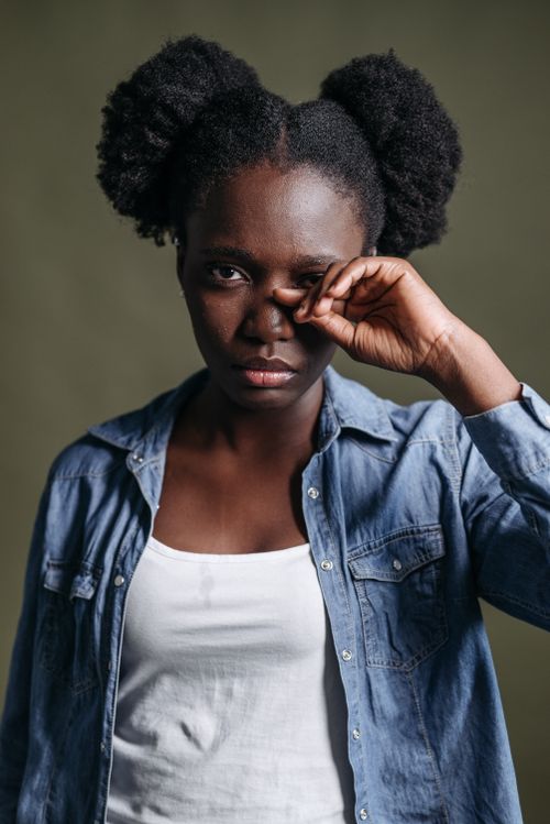 Free Studio portrait of an expressive woman with hand on face, in denim attire. Stock Photo