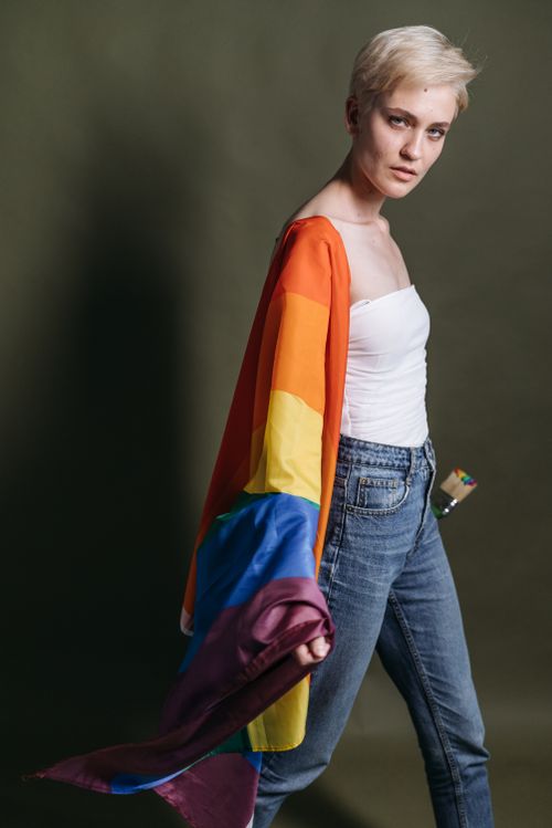 Free Stylish woman poses with a rainbow flag, symbolizing pride and diversity. Stock Photo