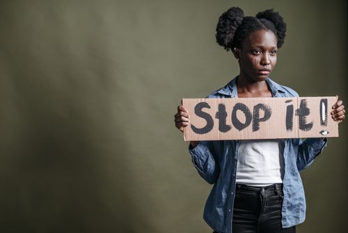Free Portrait of a woman holding a 'Stop it!' sign, conveying a powerful statement indoors. Stock Photo