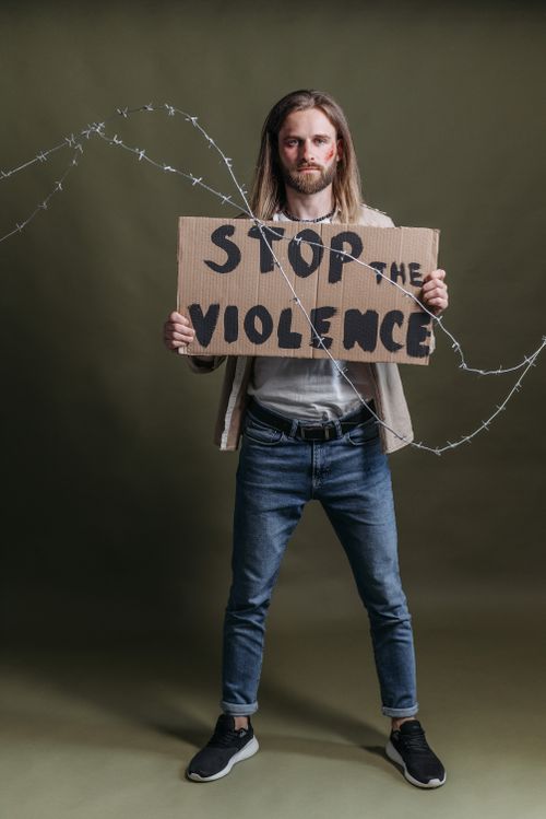 Free Man standing with a placard reading 'Stop the Violence' in a studio shoot. Stock Photo