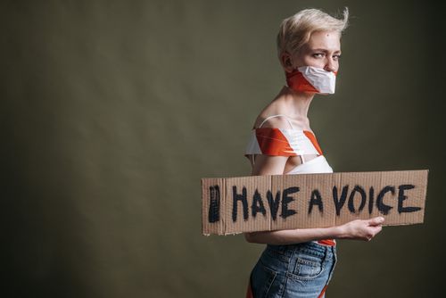 Free A woman wrapped in tape holds a protest placard saying 'I Have a Voice'. Stock Photo