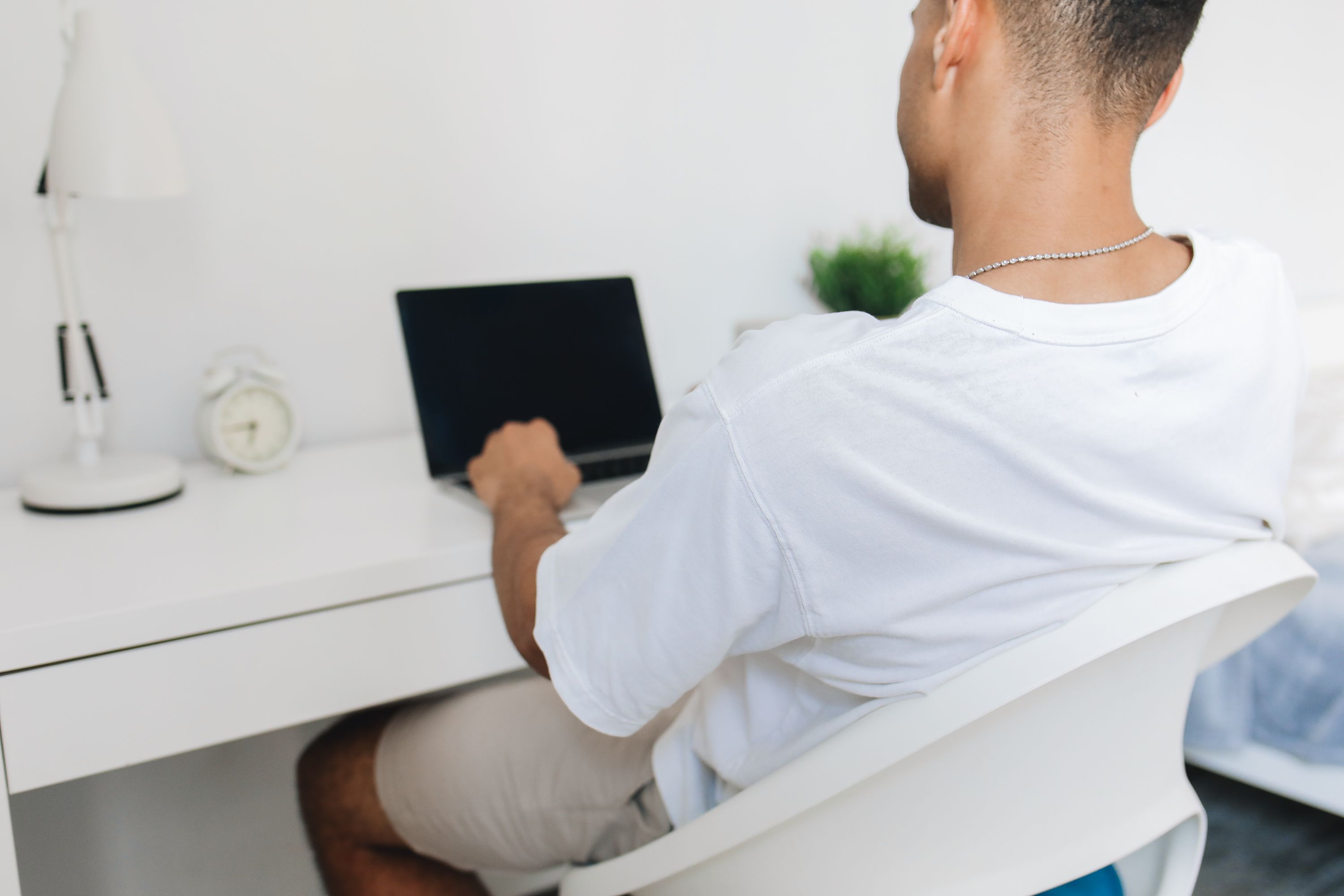 Student working at compact work desk in dorm room with laptop and office supplies