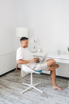 Young man focused on laptop at a sleek home desk, embodying a modern work-from-home lifestyle.
