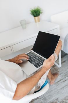 Casual scene of a man using a laptop at home, ideal for remote work themes.