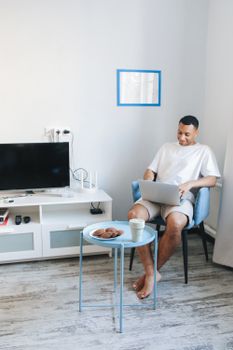 A man working on a laptop in a cozy, well-lit living room setting, enjoying remote work.