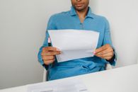 Woman in Blue Long Sleeve Shirt Holding White Paper