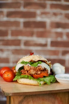 Mouth-watering fried chicken burger with fresh lettuce, tomato, and onion, served with a side dip.