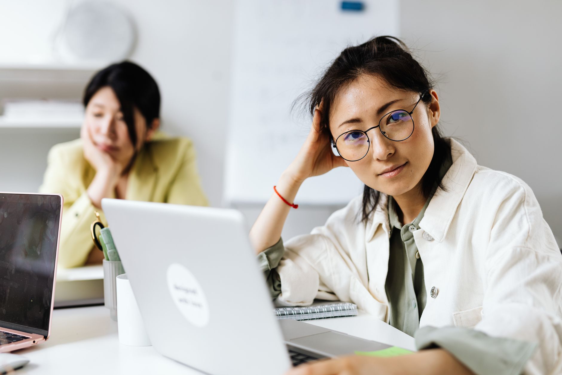 Focused woman with eyeglasses working on a laptop in an office setting.