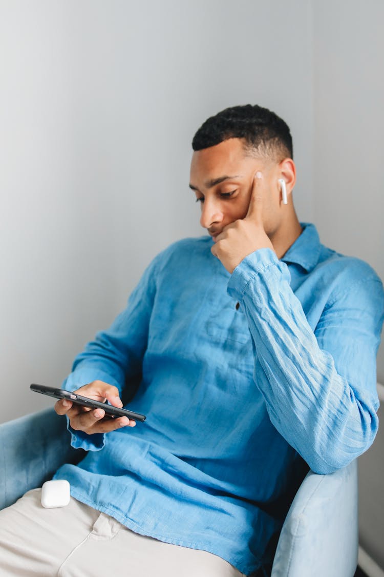 Man In Blue Long Sleeve Shirt Wearing An AirPod