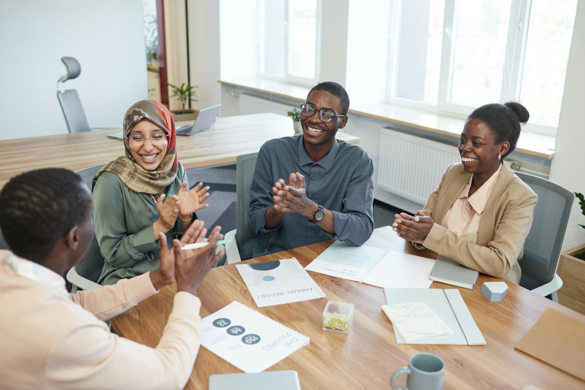 Diverse group of office workers collaborating and discussing new ideas in a bright meeting room.