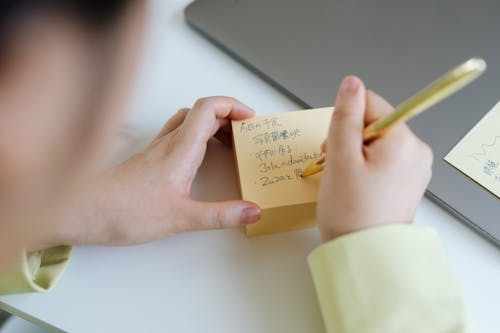 A Person Writing on a Sticky Note