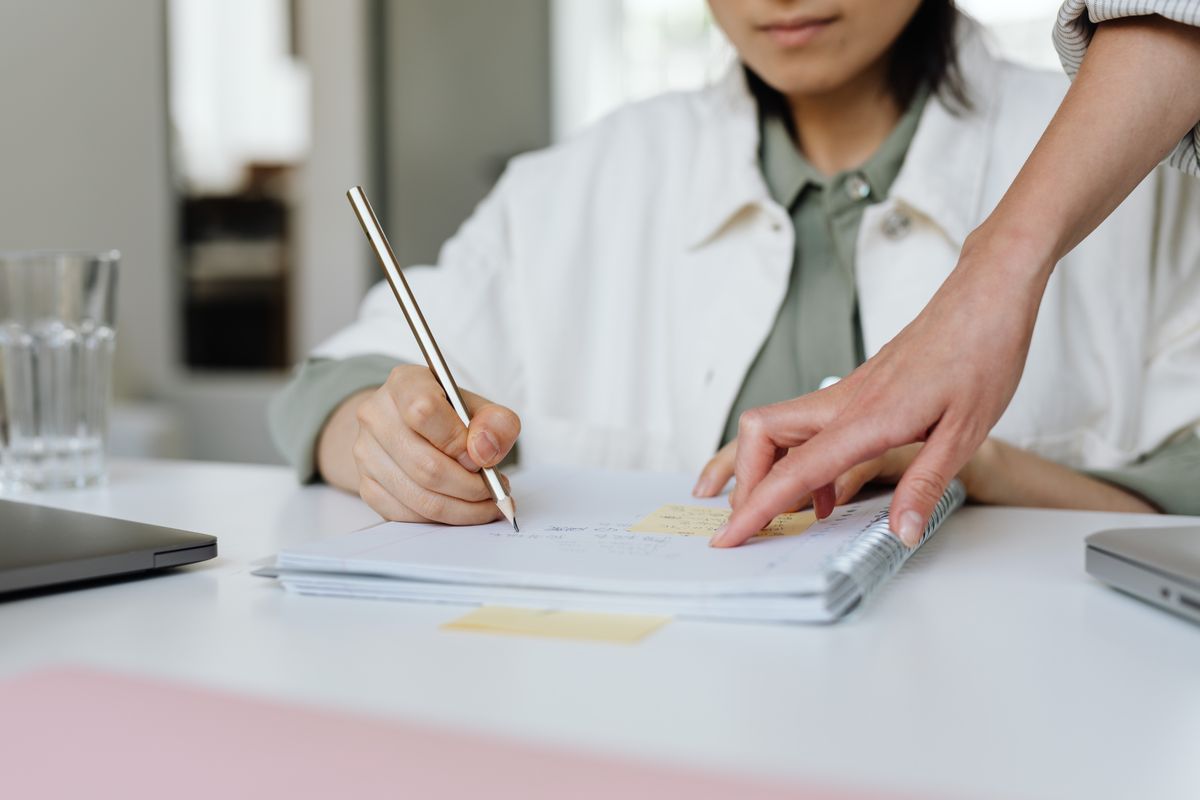 Two professionals collaborating and taking notes in a modern office setting