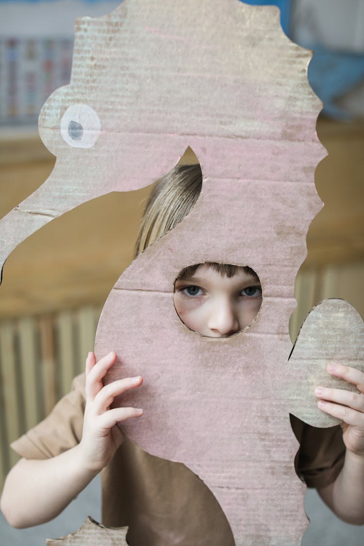 A Young Boy Holding A Cardboard Seahorse