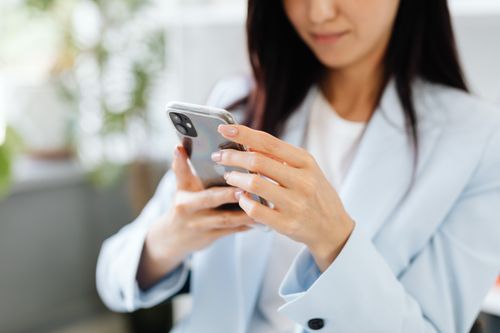 Free A woman with manicured nails uses a smartphone inside a modern setting. Stock Photo