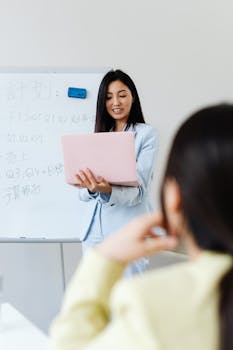 Professional woman leading a business presentation with a laptop and whiteboard.