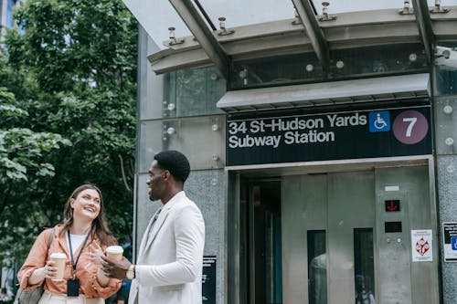 Young Man and Woman with ID Badges Standing and Talking in Front of an Elevator Entrance to a Subway Station 