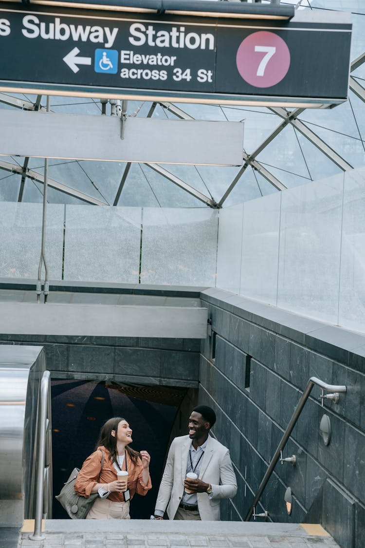 Man And Woman Talking On Steps Of Subway Entrance