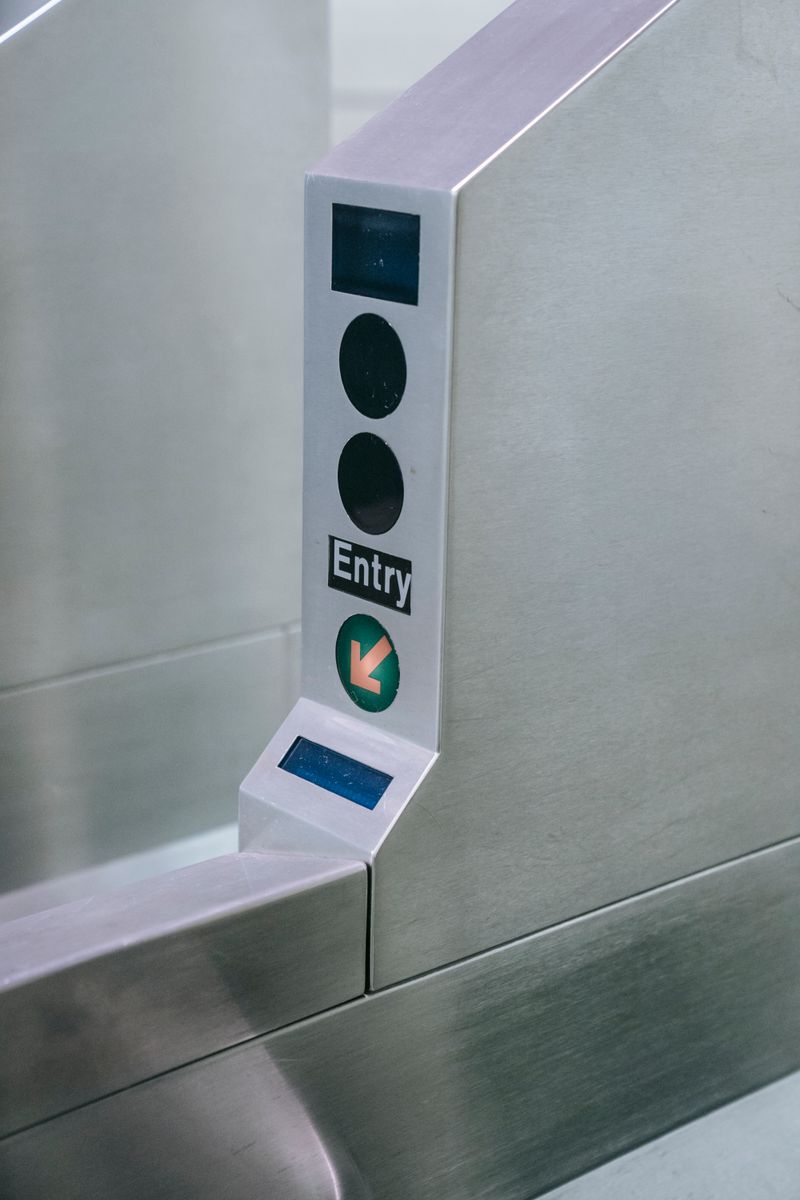 Close-up of a stainless steel entry gate with a lit directional arrow
