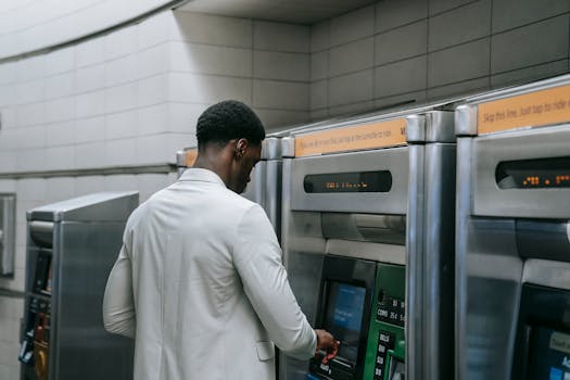 A man uses a public ticket machine in an indoor subway station setting.