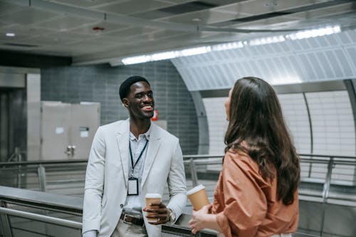 Man and a Woman Talking while Leaning on Metal Railing