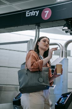Young woman with coffee enters metro station. Captured in modern subway setting.