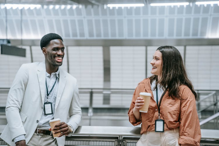 Man And Woman Wearing ID Badges Talking And Smiling 