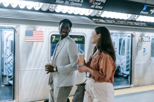Free Business colleagues enjoy a casual conversation holding coffee on a subway platform. Stock Photo